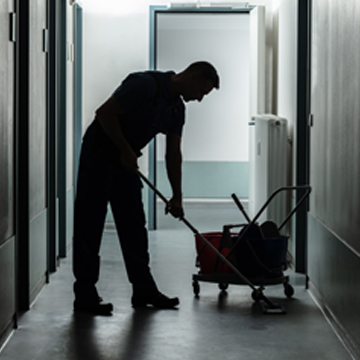 Man performing office cleaning services in Peoria IL by mopping hallway