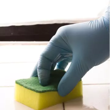 A worker's hand is seen scrubbing a tile surface. Corporate Clean is an Office Cleaning Company in Dunlap IL.