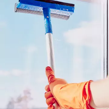 A gloved hand is seen cleaning a window. Corporate Clean offers Sanitization Services.