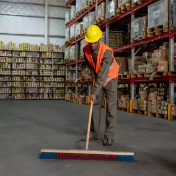 A man is seen sweeping a warehouse. Corporate Clean provides Industrial Cleaning Services in East Peoria IL.