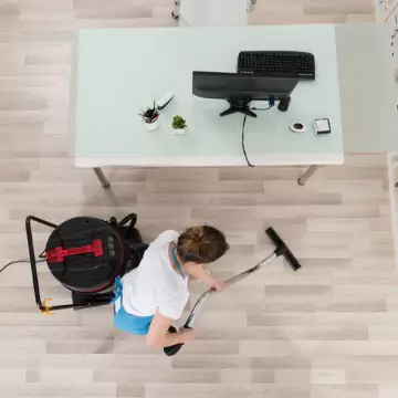 A cleaner is seen vacuuming an office. The best corporate cleaning in Peoria County IL is done by Corporate Clean.