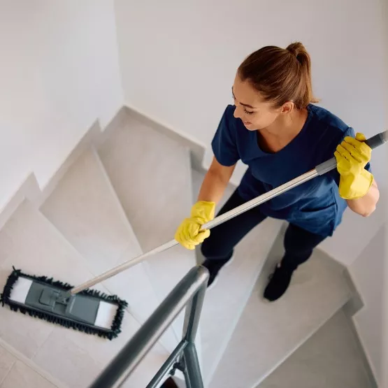 A member of Corporate Clean, which provides office & janitorial cleaning services, mops stairs in a building.