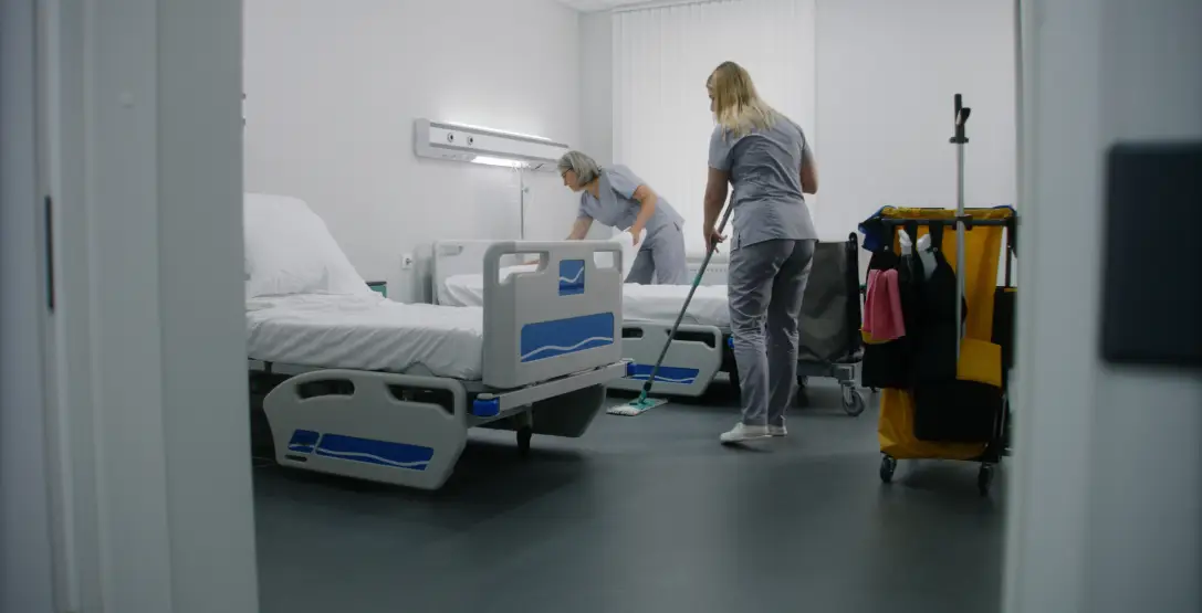 Two cleaners from Corporate Clean mop and clean bedding in a hospital room as party of the healthcare cleaning services