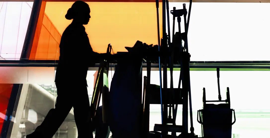 A member of Corporate Clean, which provides Industrial Cleaning services, pushes a cleaning cart down the hallway of a business