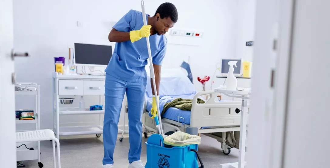 A professional cleaner helping clean the floor of a patient's room, part of Corporate Clean's floor care services