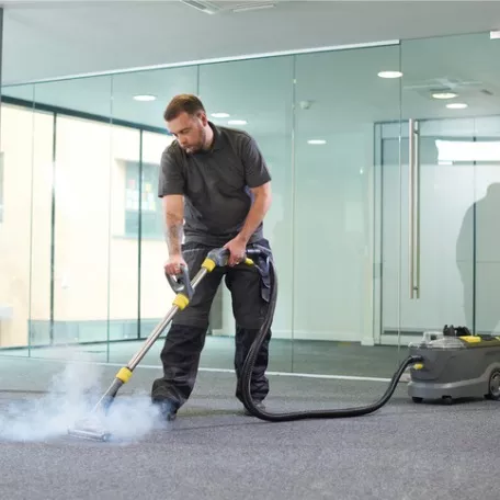 A man from Corporate Clean’s Floor Care team deep cleans the carpet in a commercial building