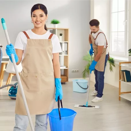 A group of staff smile and pose with cleaning tools as they perform Central Illinois Commercial Cleaning Services for Corporate Clean