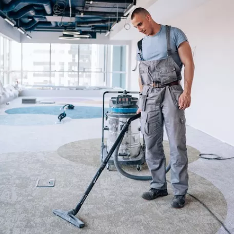 A member of Corporate Clean, an Industrial Cleaning company, vacuums carpet in a new workspace