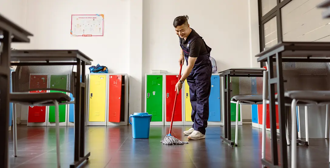 a member of the Corporate Clean team mops floors in a education setting