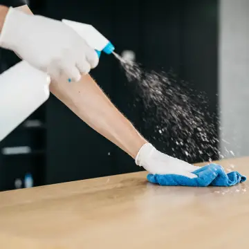 How Often Should an Office Be Professionally Cleaned? A worker sprays down a desk.